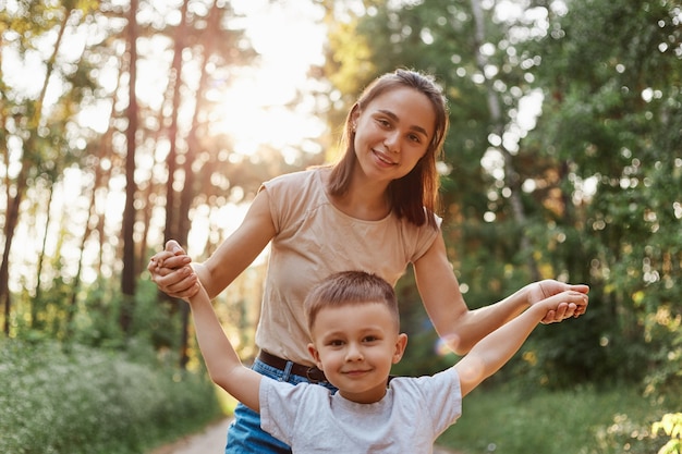 Portrait en plein air d'une belle mère de femme posant avec son petit fils séduisant, jouant et passant du temps ensemble en forêt ou dans un parc, week-end en plein air dans la nature,