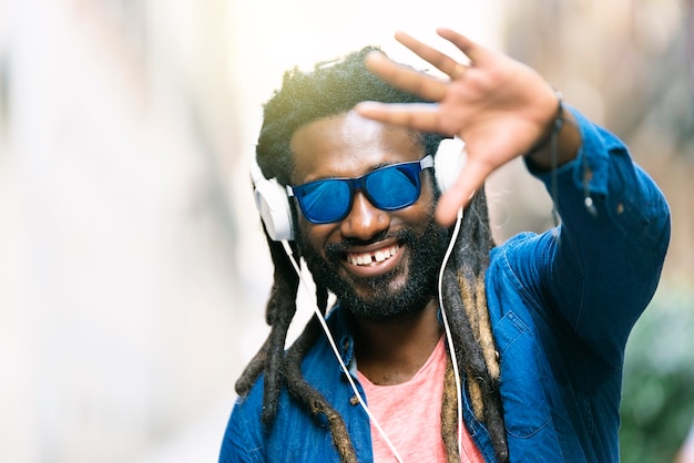 Portrait en plein air du beau jeune homme africain écoutant de la musique.