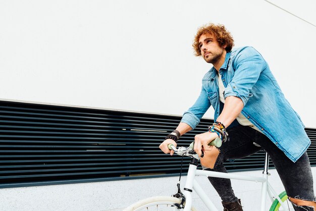 Portrait en plein air du beau jeune homme avec vélo à pignon fixe dans la rue.