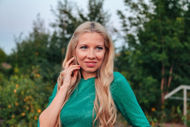 Portrait en plein air femme adulte sur la nature marchant dans la forêt d'été du crépuscule. Dame rêveuse en soirée à pied dans un parc. Émotion positive de la femme sur le parc à l'aube