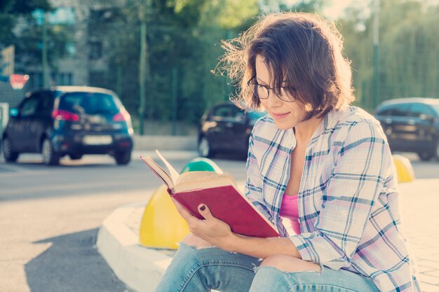 Portrait en plein air de femme mature dans des verres avec un livre.