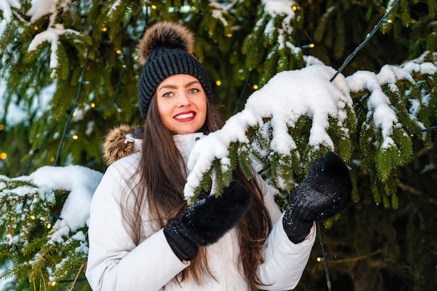 Portrait en plein air en gros plan d'une très belle jeune femme au-dessus des lumières de l'arbre de Noël en arrière-plan