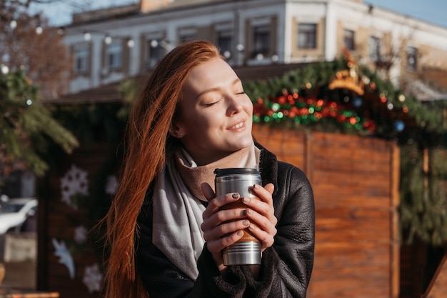 Portrait en plein air d'hiver d'une femme rousse dans des tons naturels. Jeune femme profitant de la vie