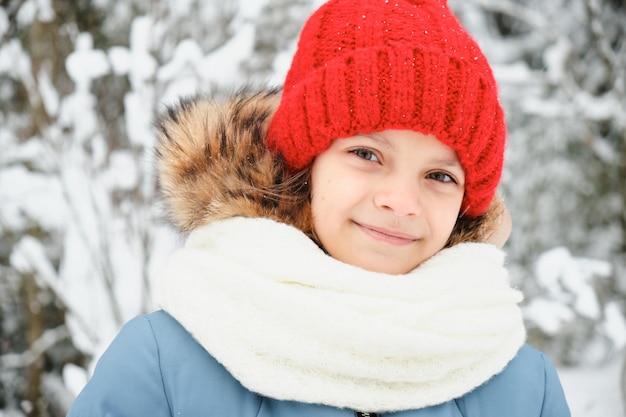 Portrait en plein air d'hiver en gros plan d'une adorable adolescente en bonnet tricoté et écharpe blanche