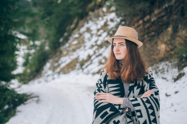 Portrait en plein air d'une jeune femme entourée d'un concept de tourisme de forêts et de montagnes couvertes de neige