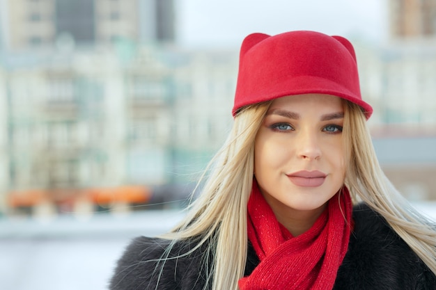 Portrait en plein air d'une jolie fille portant une casquette rouge élégante et une écharpe tricotée