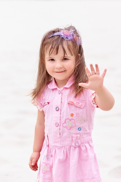 Portrait en plein air de jolie petite fille en robe sur le sable de la plage.