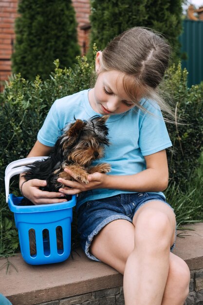 Photo portrait en plein air d'un mignon chiot de yorkshire terrier dans un panier et d'une fille préadolescente