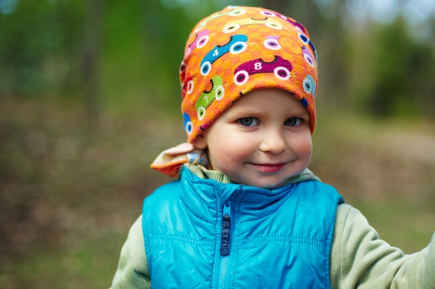 Portrait en plein air de mignon enfant garçon sur naturel foncé