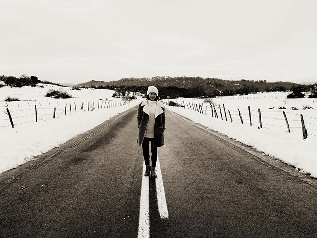 Photo portrait en pleine longueur d'une femme marchant sur la route contre le ciel pendant l'hiver