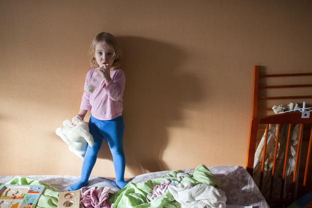 Photo portrait en pleine longueur d'une fille tenant un jouet sur le lit à la maison