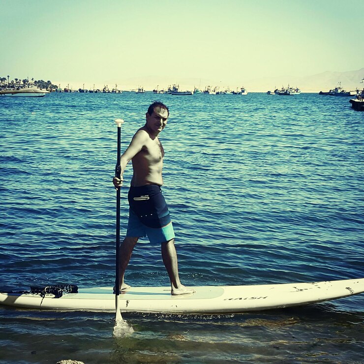 Photo portrait en pleine longueur d'un homme sans chemise faisant du paddleboard en mer