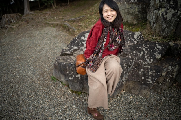 Photo portrait en pleine longueur d'une jeune femme souriante assise sur des rochers