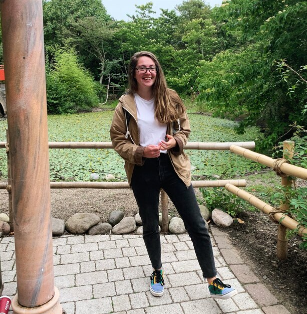 Portrait en pleine longueur d'une jeune femme souriante à l'extérieur