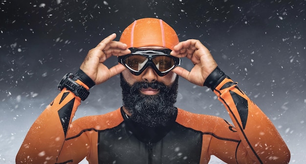 Portrait de plongeur barbu sous des gouttes de pluie sur fond de montagnes enneigées.