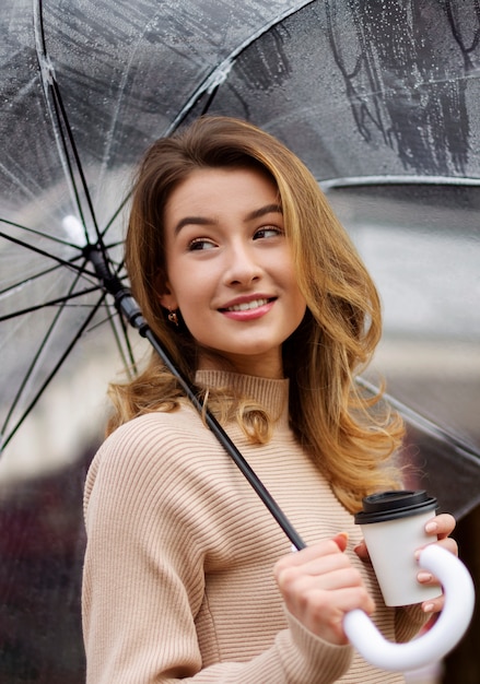 Portrait de pluie de belle jeune femme avec parapluie