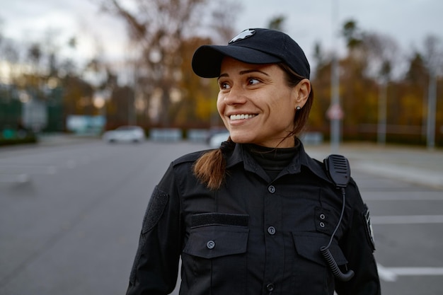 Portrait d'une policière souriante dans la rue regardant de côté. Tourné avec un arrière-plan flou