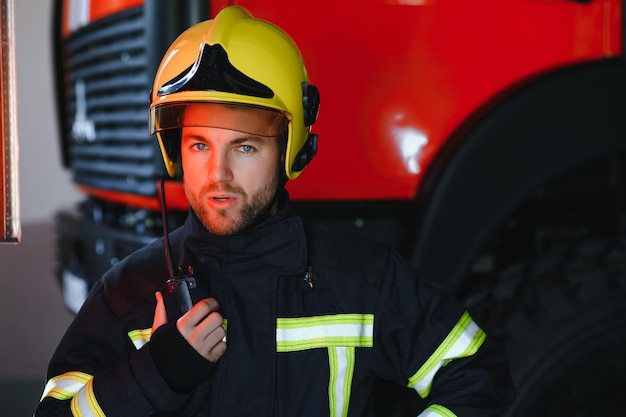 Photo portrait de pompier en service photo pompier avec masque à gaz et casque près de la pompe à incendie