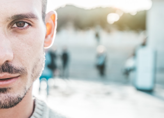 Portrait de près d'un beau jeune homme de race blanche en plein air. Demi visage.