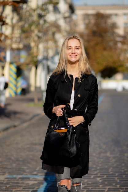 Portrait de printemps ensoleillé d'un modèle blond joyeux profitant du temps chaud, marchant dans la rue