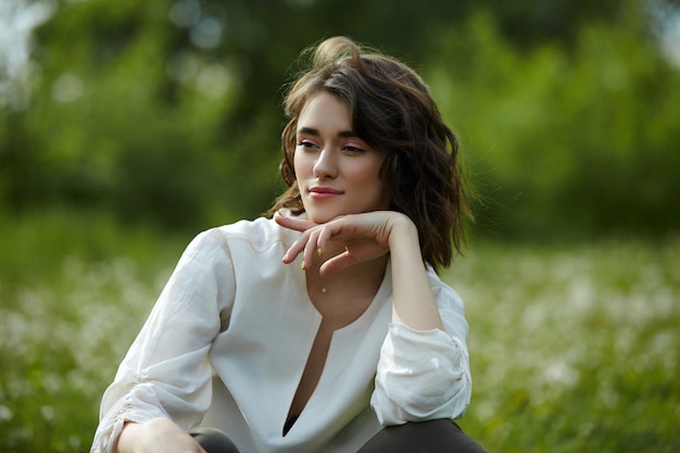 Portrait de printemps d'une jeune fille assise dans un champ sur l'herbe parmi les fleurs de pissenlit. Fille gaie aime le temps de printemps ensoleillé. Beauté naturelle d'une femme, cosmétiques naturels