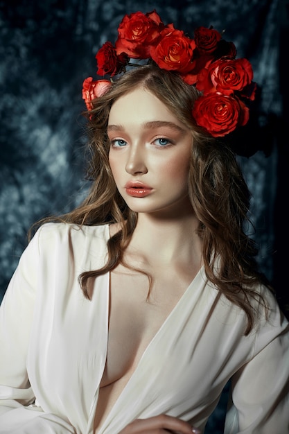 Portrait de printemps romantique d'une jeune femme blonde avec une couronne de fleurs rose rouge