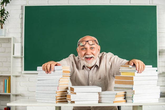 Portrait d'un professeur dans la classe Un professeur drôle qui tient beaucoup de livres à l'école Un professeur avec des livres dans sa poche