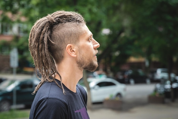 Portrait de profil d'un homme de race blanche avec barbe et sidecut dreadlocks sur une piscine d'été