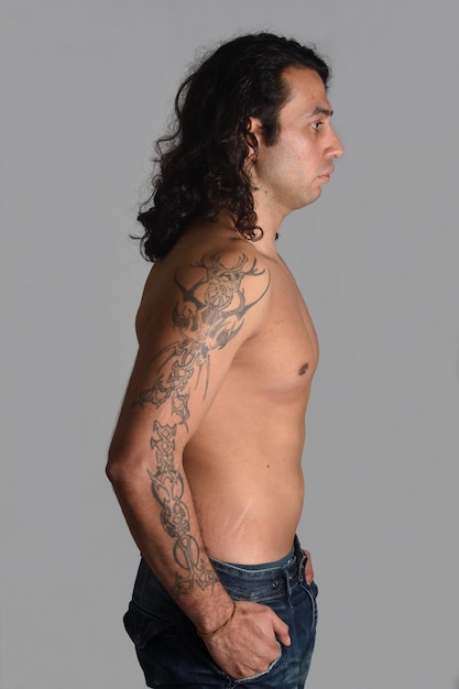 Portrait de profil d'un homme avec des tatouages sur fond gris