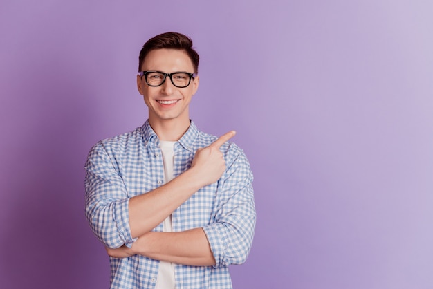 Portrait d'un promoteur positif indiquant l'espace vide du doigt sur fond violet