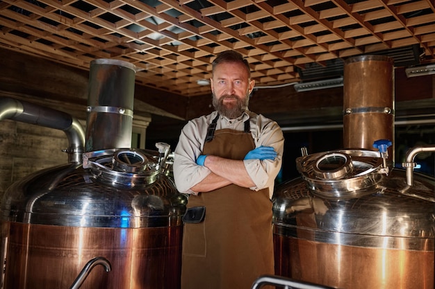 Portrait d'un propriétaire de brasserie mature portant un tablier avec les bras croisés