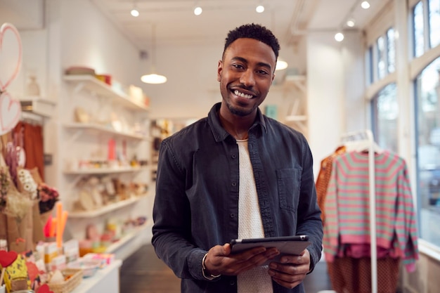 Portrait d'un propriétaire de petite entreprise masculine vérifie le stock dans la boutique à l'aide d'une tablette numérique