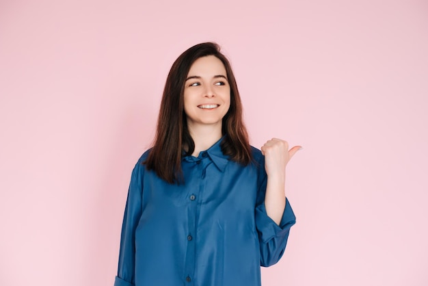 Portrait radieux d'une belle femme avec un sourire joyeux pointant du doigt et regardant l'espace vide