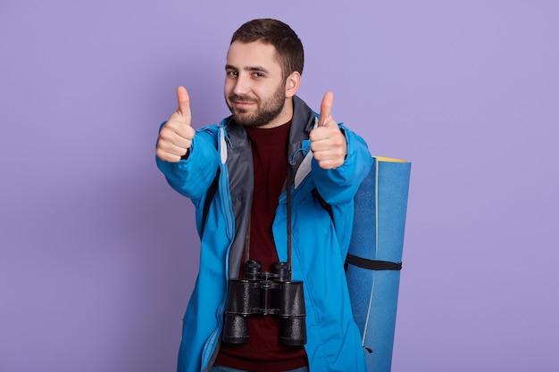 Portrait de randonneur avec sac à dos posant isolé sur fond lilas