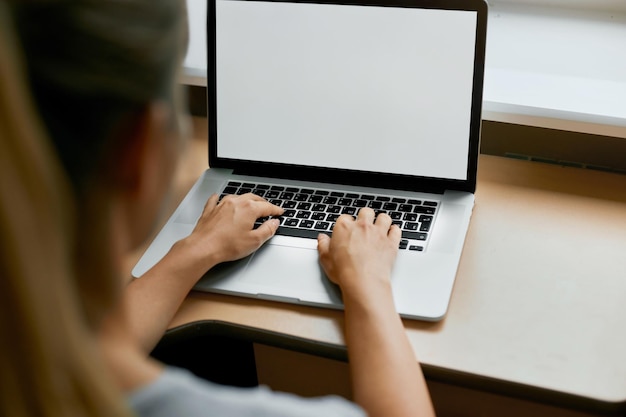 Portrait recadré d'une employée tapant sur le clavier d'un ordinateur portable générique travaillant sur un rapport financier