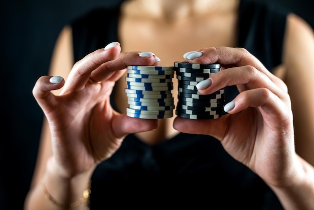 Portrait recadré de femme en robe noire tenant des jetons devant le clivage pour jouer Jeux de poker pour adultes Jetons de poker dans des mains féminines isolées sur fond noir