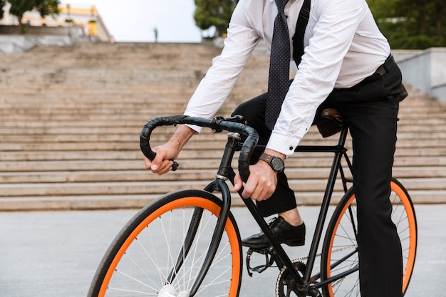 Portrait recadré d'un homme d'affaires portant un costume, portant une mallette à l'extérieur à vélo