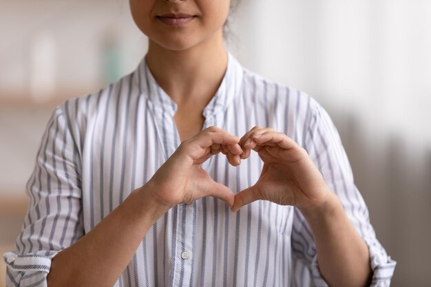 Portrait recadré d'une jeune patiente cardio exprimant sa gratitude sincère aux cardiologues bénévoles donateurs caritatifs Gros plan d'une femme du millénaire posant devant la caméra montrant le coeur du doigt