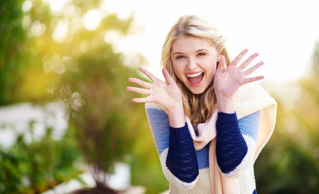 Portrait recadré surprise d'une jeune femme gesticulant avec enthousiasme à l'extérieur