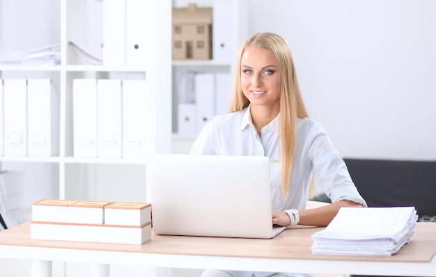 Portrait d'une réceptionniste souriante utilisant un ordinateur portable et un casque au bureau