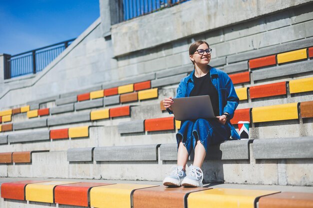 Portrait d'un rédacteur indépendant joyeux dans des lunettes optiques pour la protection de la vision souriant à la caméra profitant d'un style de vie nomade numérique heureux professionnel de l'informatique Caucaisan avec un netbook moderne