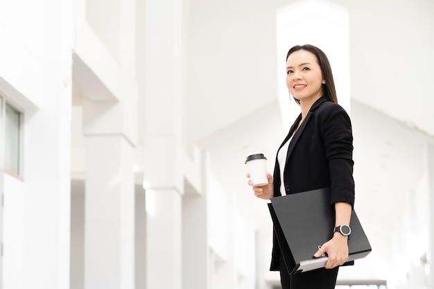 Portrait de réussite d'une femme d'affaires asiatique d'âge moyen tenant un café souriant à la caméra