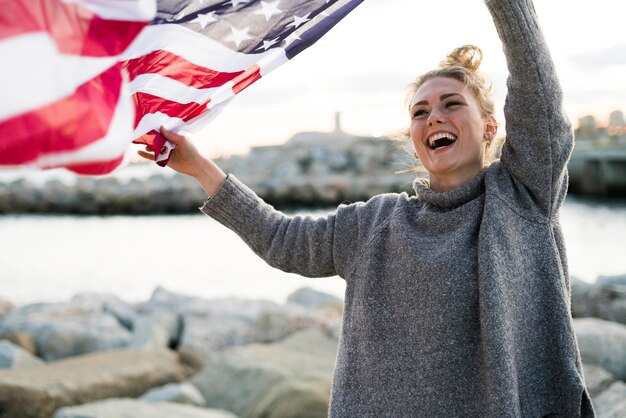 portrait, de, rire, jeune femme, tenue, souffler, nous, drapeau américain