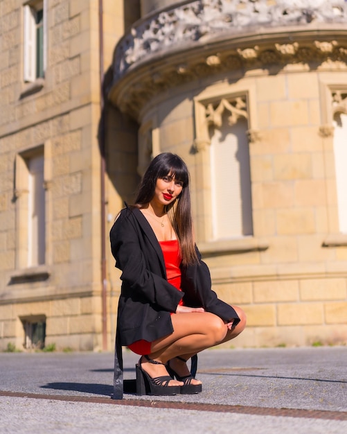 Portrait en robe rouge dans le beau château jolie fille accroupie posée en souriant