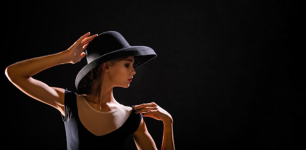 Photo portrait romantique de belle jeune fille sur un fond noir dans un chapeau élégant