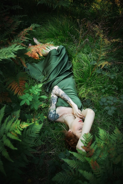 Portrait romantique d'une femme dans une fougère dans la forêt. Art femme maquillage naturel au repos dans la nature. Fourrés de fougères vertes