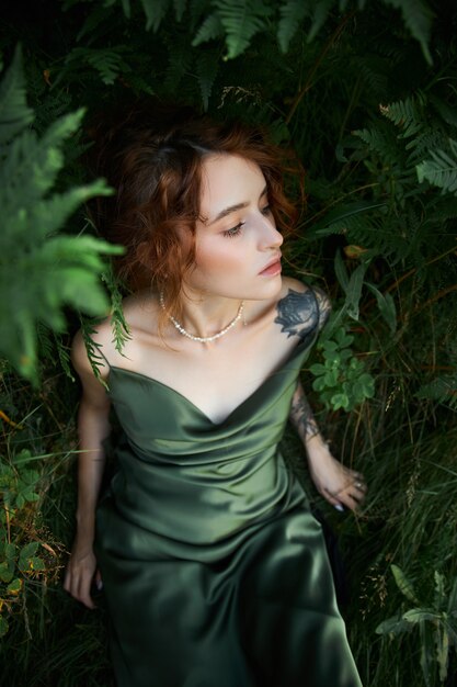 Portrait romantique d'une femme dans une fougère dans la forêt. Art femme maquillage naturel au repos dans la nature. Fourrés de fougères vertes