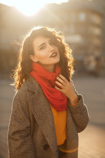 Portrait de rue d'un adorable mannequin brune posant en contre-jour doux en soirée