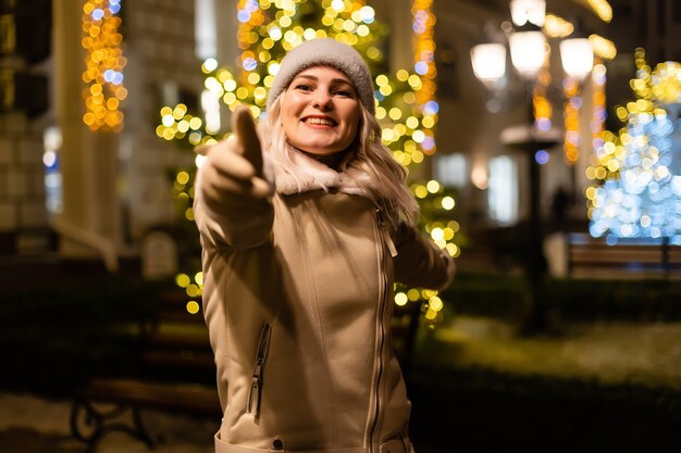 Portrait de rue d'une belle jeune femme souriante sur la foire de Noël festive. Dame portant des vêtements tricotés d'hiver élégants classiques.