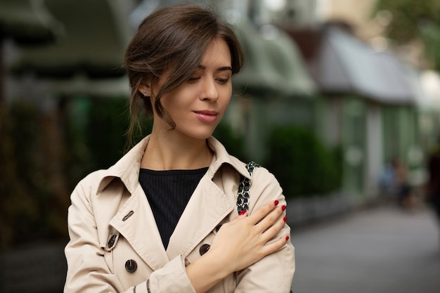 Portrait de rue de mode d'une femme brune élégante avec un maquillage naturel porte un élégant manteau beige, marchant dans la ville d'automne. Espace pour le texte